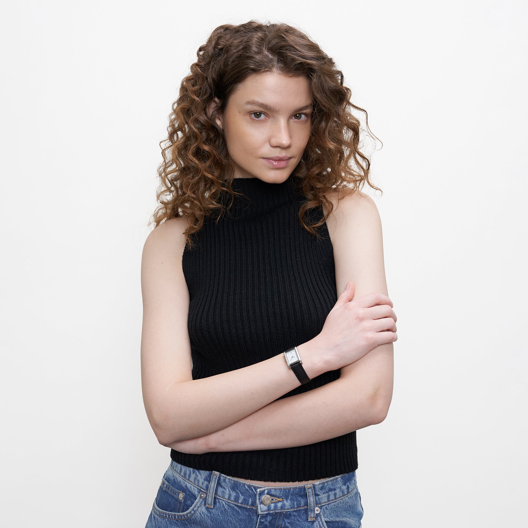 LIEBESKIND BERLIN Damenarmbanduhr im rechteckigen Design mit schwarzem Lederarmband am Handgelenk eines Models mit schwarzem Top.