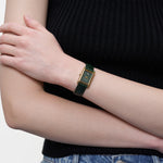 Nahaufnahme der getragenen LIEBESKIND BERLIN Damenarmbanduhr mit grünem Zifferblatt, goldfarbenem Gehäuse und dunkelgrünem Lederarmband.