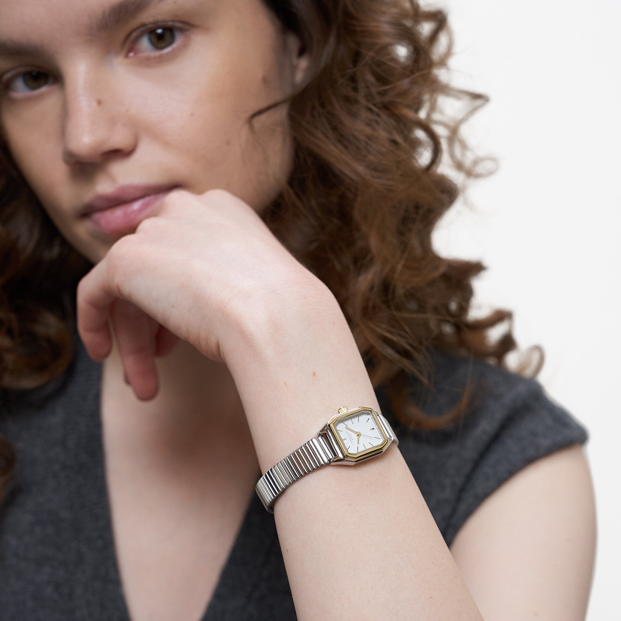 LIEBESKIND BERLIN Damenarmbanduhr in Bicolor mit weißem Zifferblatt und silberfarbenem Edelstahlarmband am Handgelenk getragen.