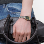 LIEBESKIND BERLIN Damenarmbanduhr in Bicolor mit grünem Zifferblatt und silberfarbenem Edelstahlarmband am Handgelenk getragen.