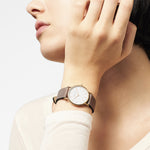 Eine Person trägt die LIEBESKIND BERLIN Armbanduhr - The Vintage Must-Have von Liebeskind Berlin mit weißem Zifferblatt, Lederarmband im Vintage-Look und minimalistischem skandinavischem Design.