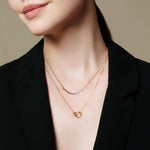 Eine Frau, die von den Schultern bis zu den Lippen vor einem schlichten Hintergrund gezeigt wird, trägt die Ania Haie Halskette - Gold Arc Pavé von Ania Haie über einem schwarzen Blazer.