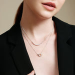 Frau trägt einen schwarzen Blazer und zwei zarte Ania Haie Halsketten, darunter die Silver Arc Pavé Halskette von Ania Haie, beide in 925 Sterling Silber mit kleinen Anhängern gefertigt.