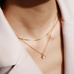 Tragebeispiel der ANIA HAIE Mother of Pearl Halskette – elegante Goldkette mit schimmerndem Perlmutt-Anhänger getragen im Layering-Look.