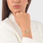 Goldfarbenes Philipp Plein Armband mit sechseckigem Schmuckelement und funkelndem Steinbesatz am Handgelenk eines Models