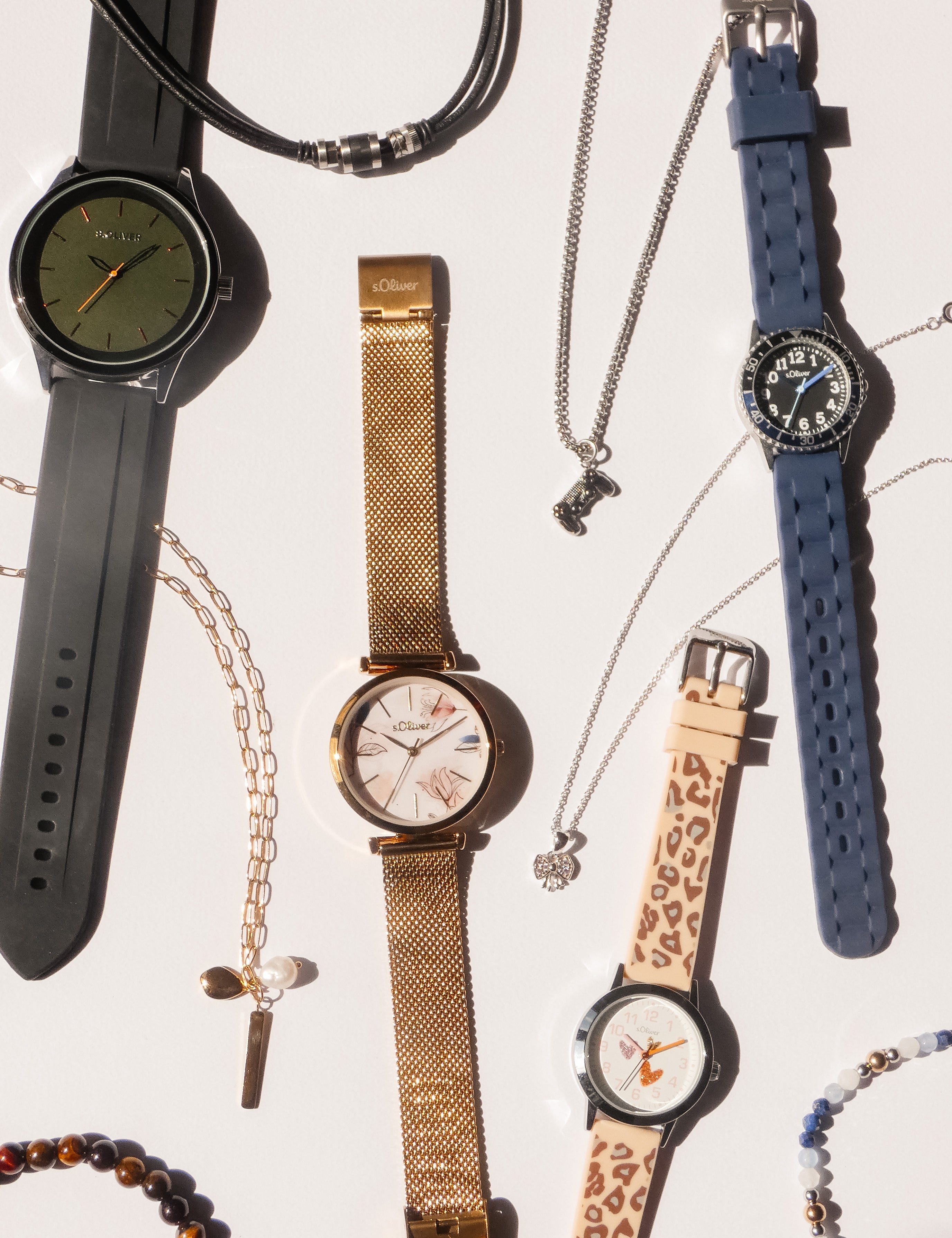 Auswahl an s.Oliver Uhren und Schmuck für Damen, Herren und Kinder mit verschiedenen Armbändern und Accessoires auf hellem Hintergrund.