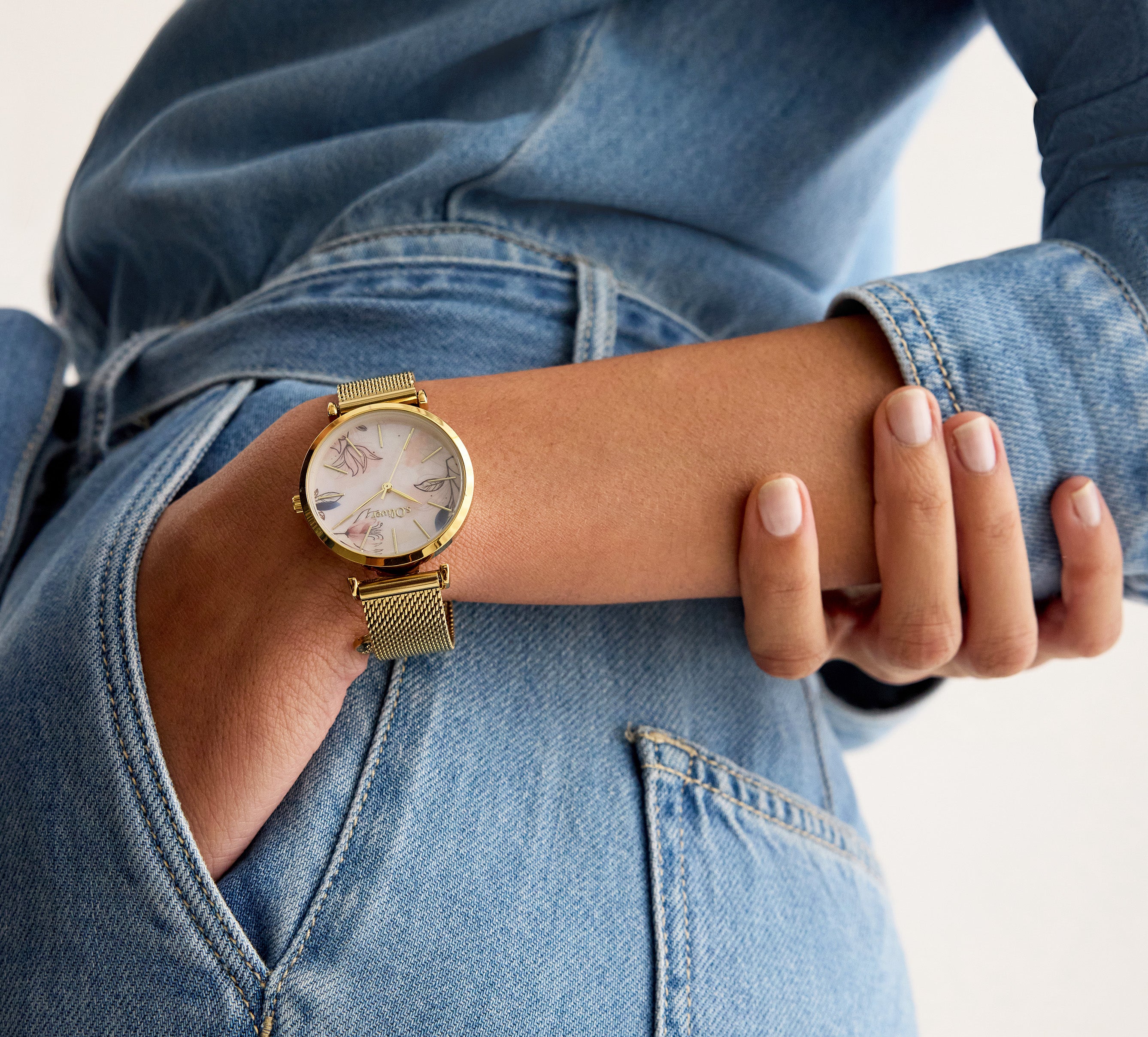 Tamaris Damenuhr in Gold mit Mesh-Armband am Handgelenk – elegante Armbanduhr kombiniert mit Denim-Look.