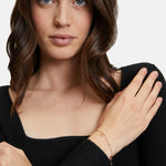 Eine Frau in einem schwarzen Oberteil trägt das Tamaris Armband - Flower an ihrem linken Handgelenk und posiert mit der Hand auf ihrer Schulter.