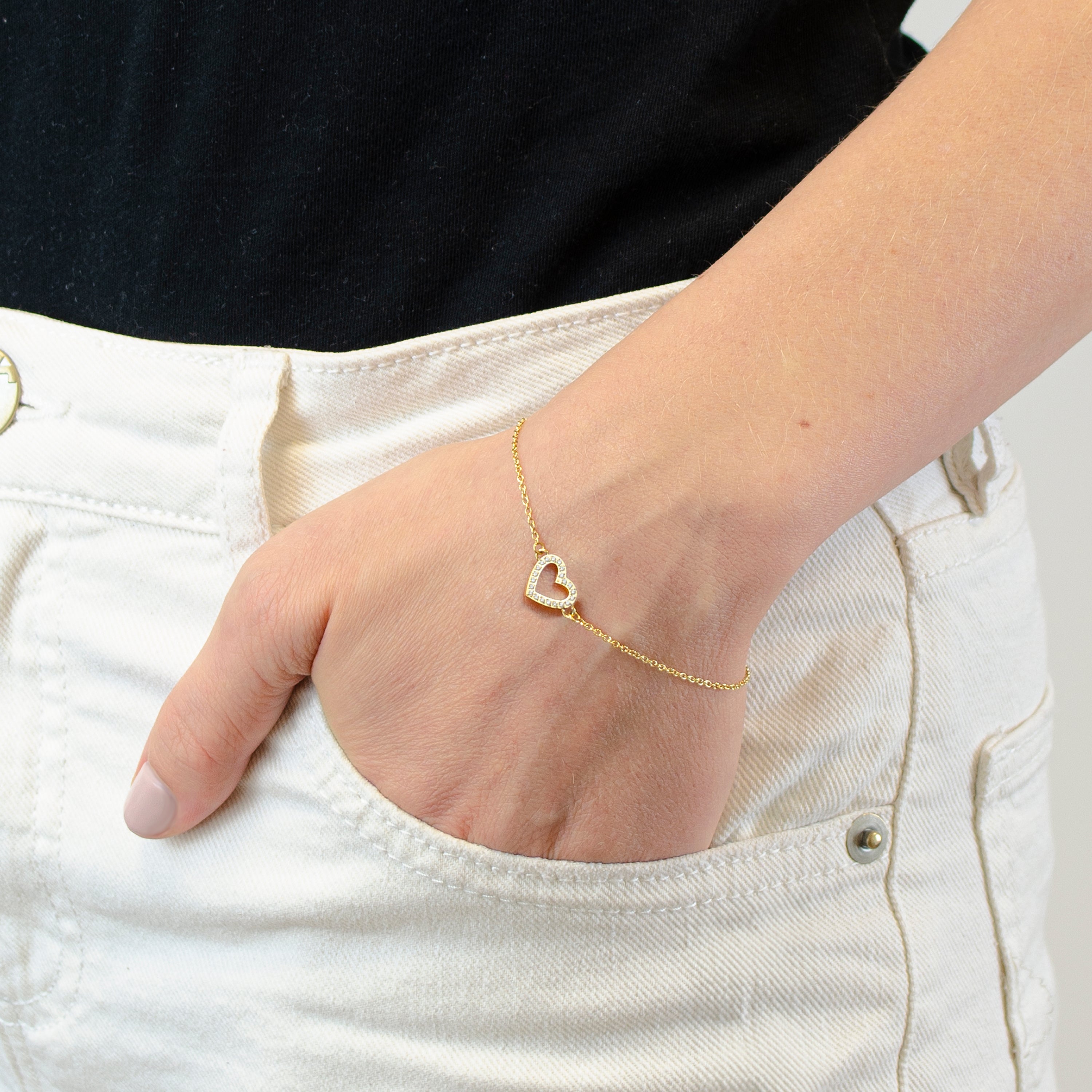 Eine Hand in einer weißen Tasche trägt das Tamaris Armband - Sparkling Hearts von Tamaris mit einem schimmernden Herzanhänger - ein stilvolles Geschenk für jeden Anlass.