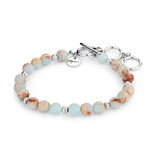 Das Tamaris Beads - Agalmatolith Armband von Tamaris hat runde blaue und braune Perlen, silberne Spacer und einen schicken silbernen Knebelverschluss.