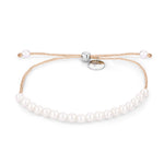 Das Tamaris Armband - The Pearl Beads von Tamaris zeigt eine goldene Kette, weiße Perlen, zarte Glitzerfäden und einen verstellbaren Verschluss auf weißem Hintergrund.