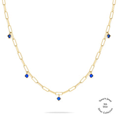 Tamaris Halskette - Die Silber Kollektion von Tamaris: Gold Gliederkette aus 925er Sterling Silber mit fünf gleichmäßig angeordneten blauen Edelsteinanhängern, auf weißem Hintergrund präsentiert.