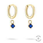 Tamaris Creole - Die Silberkollektion: Goldfarbene Creolen mit blauen Zirkonia-Anhängern, 925er Sterlingsilber, auf weißem Hintergrund mit dem Tamaris-Logo in der Ecke.