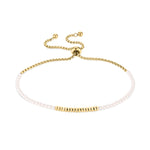 Das Tamaris Armband - Modern Pearl Fusion hat goldene und weiße Glasperlen, einen verstellbaren Zugbandverschluss und ist auf einem weißen Hintergrund abgebildet.