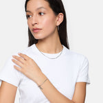 Frau im weißen T-Shirt trägt Tamaris Creole - Modern Chain Ohrringe und Silberschmuck und schaut mit der Hand auf der Schulter zur Seite.