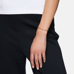 Eine Person, die eine schwarze Hose und ein weißes Oberteil trägt, mit dem Tamaris Armband - Modern Chain, einem stilvollen Armband von Tamaris, an ihrem Handgelenk.