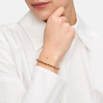 Tamaris Damenarmband aus goldfarbenem Edelstahl mit Kugeldesign und verstellbarem Zugverschluss am Handgelenk getragen.
