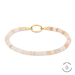 Das Tamaris Armband - All About Beads besteht aus hellpfirsich- und cremefarbenen Scheibenperlen, beigen Steinen, einem goldenen Verschluss und dem kultigen Tamaris Jewel Charms Logo.