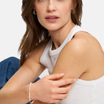 Frau in weißem Tanktop und Jeans trägt das Armband Tamaris - All About Beads und schaut mit neutralem Blick in die Kamera.