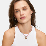 Frau mit braunen Haaren in einem weißen Tank-Top, trägt die Tamaris Halskette - All About Beads von Tamaris und schaut in die Kamera.