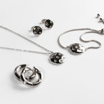 Tamaris Ohrstecker - Little Twinkle: Funkelnde Silberohrringe mit Zirkonia im Stern-Design von Tamaris, dazu passende Halsketten und ein Armband auf weißem Grund.