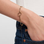 Ein Tamaris Armband aus der Charm Series - ein goldenes Kettenarmband mit kreisförmigen Gliederkettengliedern - verleiht dem Damenschmuck einen eleganten Touch, wenn er mit Blue Denim Jeans am Handgelenk getragen wird.