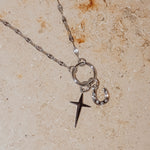 Die Tamaris Halskette - Charm Series von Tamaris ist mit einem Stern und einem mit Edelsteinen besetzten Halbmond-Anhänger versehen, der auf einer strukturierten beigen Oberfläche elegant zur Geltung kommt - ein stilvolles Accessoire für jeden Anlass.