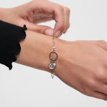 Das Armband Tamaris Charms Bundle - Charm Series von Tamaris mit Herz, Schlüsselanhänger und funkelnden Zirkonia-Akzenten wird von einer Hand um das Handgelenk geschlossen.