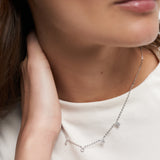 Nahaufnahme einer Frau, die die Tamaris Halskette aus der Silver Love Collection mit Zirkoniasteinen, LOVE-Anhängern und einem passenden LOVE-Ohrring von Tamaris trägt.