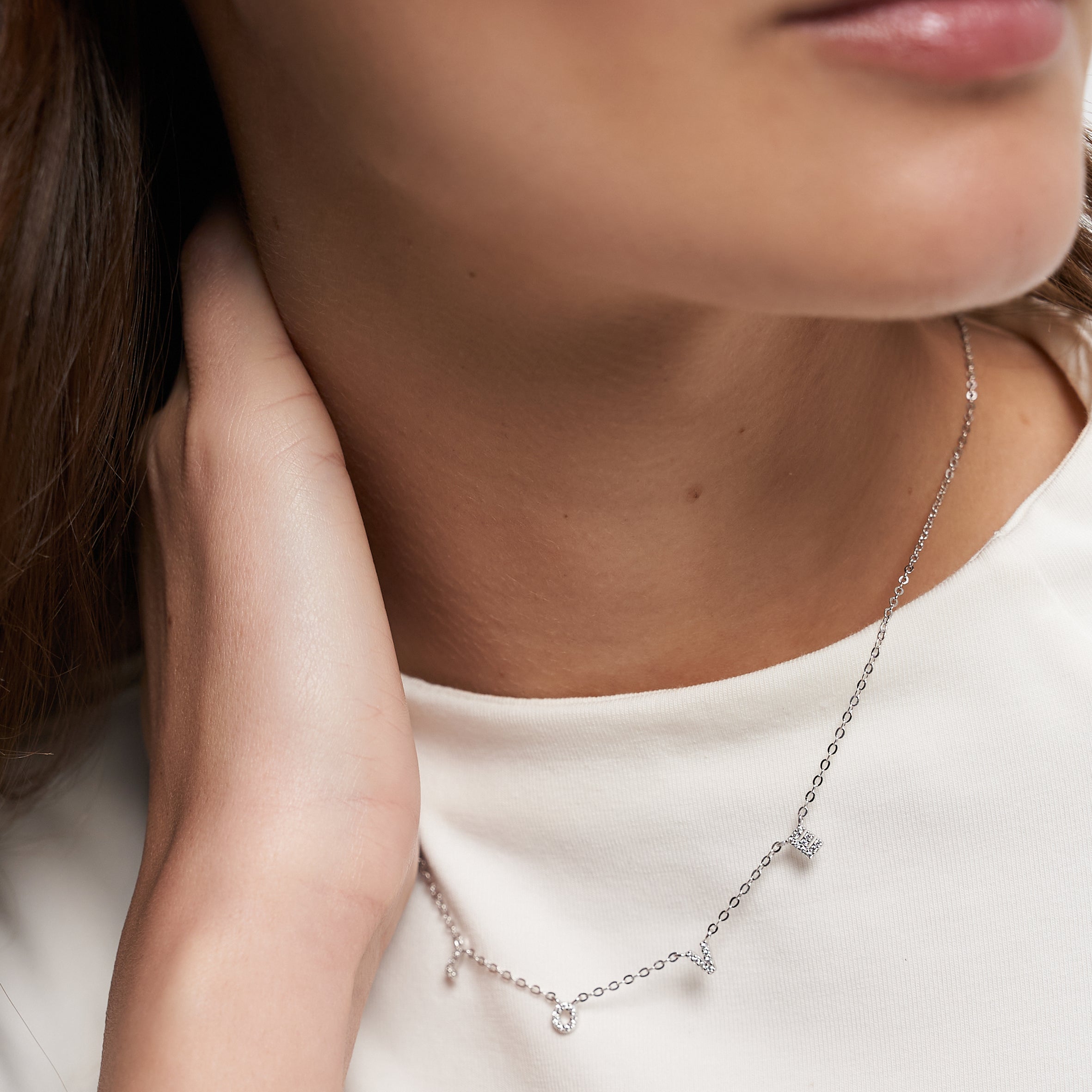 Nahaufnahme einer Frau, die die Tamaris Halskette aus der Silver Love Collection mit Zirkoniasteinen, LOVE-Anhängern und einem passenden LOVE-Ohrring von Tamaris trägt.