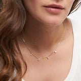 Eine Frau trägt die Tamaris Halskette aus der Silver Love Collection mit LOVE Anhänger und funkelnden Zirkoniasteinen, kombiniert mit einem schlichten weißen Top.