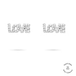 Die Tamaris Ohrstecker aus der Silver Love Collection zeigen den Schriftzug "LOVE" und sind mit glänzenden Zirkonia-Steinen verziert. Präsentiert auf weißem Hintergrund.