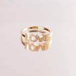 Der Tamaris Ring aus der Silver Love Collection ist mit einem LOVE Schriftzug versehen, der mit funkelnden Zirkonia verziert ist und sich auf einer glänzenden Oberfläche spiegelt.