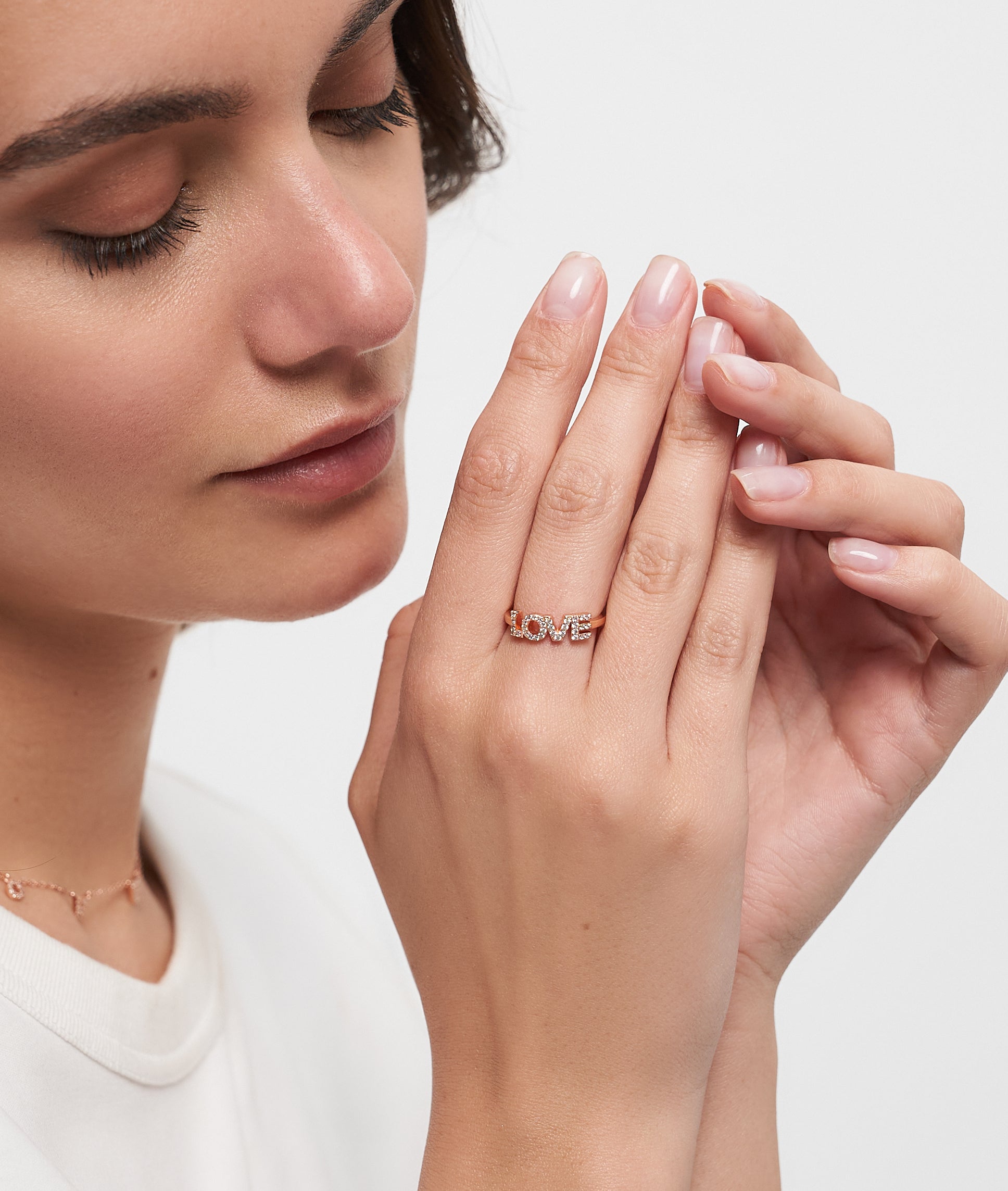 Frau mit geschlossenen Augen, die ihr Gesicht berühren, trägt einen Tamaris Ring aus der Silver Love Collection von Tamaris, der mit funkelnden Zirkonen verziert ist.