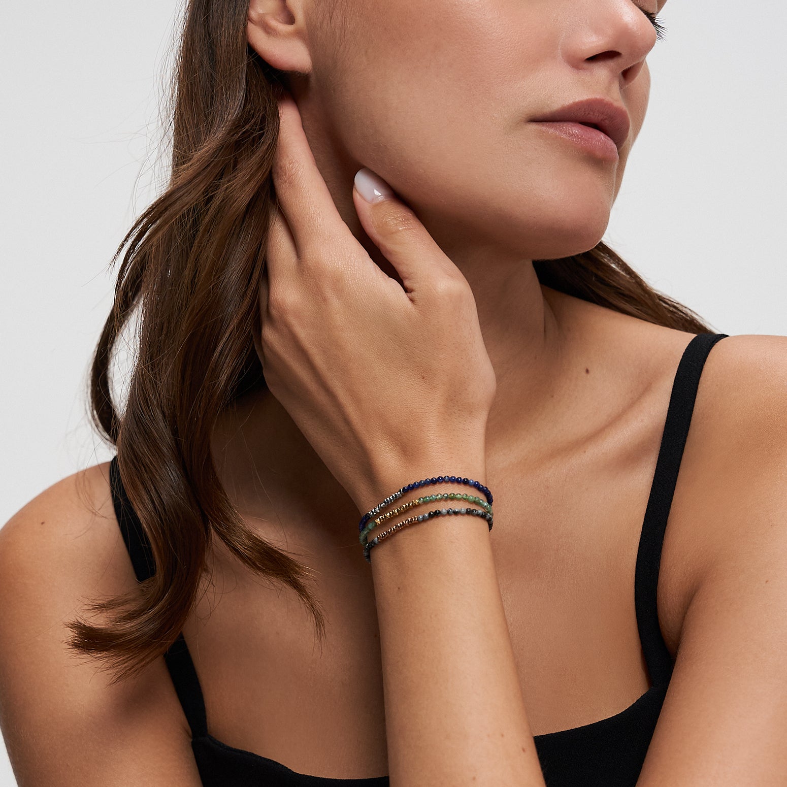 Tamaris Damenarmband mit grünem Naturstein, goldfarbenen Edelstahlelementen und praktischem Zugverschluss am Handgelenk getragen.