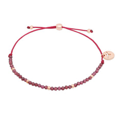 Das Tamaris Armband - Beads by Tamaris ist ein dünnes rotes Armband mit kleinen rosafarbenen und goldenen Perlen sowie einem runden Anhänger mit einem minimalistischen Vogelmotiv.