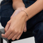 Roségoldfarbene Tamaris Armband mit geschwungenem Herzanhänger am Arm eines Models, kombiniert mit passenden Herz-Ohrsteckern