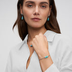 Silberfarbenes Tamaris Damen Armband mit türkisfarbenen Schmucksteinen am Handgelenk, kombiniert mit passendem Schmuck