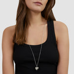 Frau im schwarzen Tank-Top trägt die Tamaris Halskette - Heart Amulet, einen eleganten herzförmigen Anhänger von Tamaris - perfekt als Geschenkidee.
