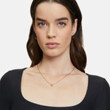 Frau mit langen braunen Haaren trägt ein schwarzes Oberteil mit quadratischem Ausschnitt, goldene Ohrringe und das Tamaris Set - The Layer Collier von Tamaris.
