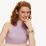 Model trägt Tamaris Damenuhr mit goldfarbenem Edelstahlarmband und Zirkonia-Lünette kombiniert mit filigranem Armband.