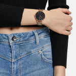 Person, die ein schwarzes langärmeliges Oberteil, blaue Jeans und die Tamaris Armbanduhr - The Modern Classic by Tamaris am linken Handgelenk trägt.