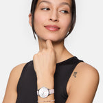Eine Frau in einem ärmellosen schwarzen Oberteil trägt eine rosafarbene Uhr und ein "m"-Tattoo auf dem Oberarm. Sie trägt das Tamaris Armband - Modern Pearl Fusion als schickes Accessoire für Frauen.