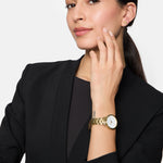 Eine Frau in einem schwarzen Blazer zeigt die Tamaris Armbanduhr - The Elegance mit Edelstahlband und funkelnden Zirkoniasteinen, berührt sanft ihr Gesicht und lächelt.