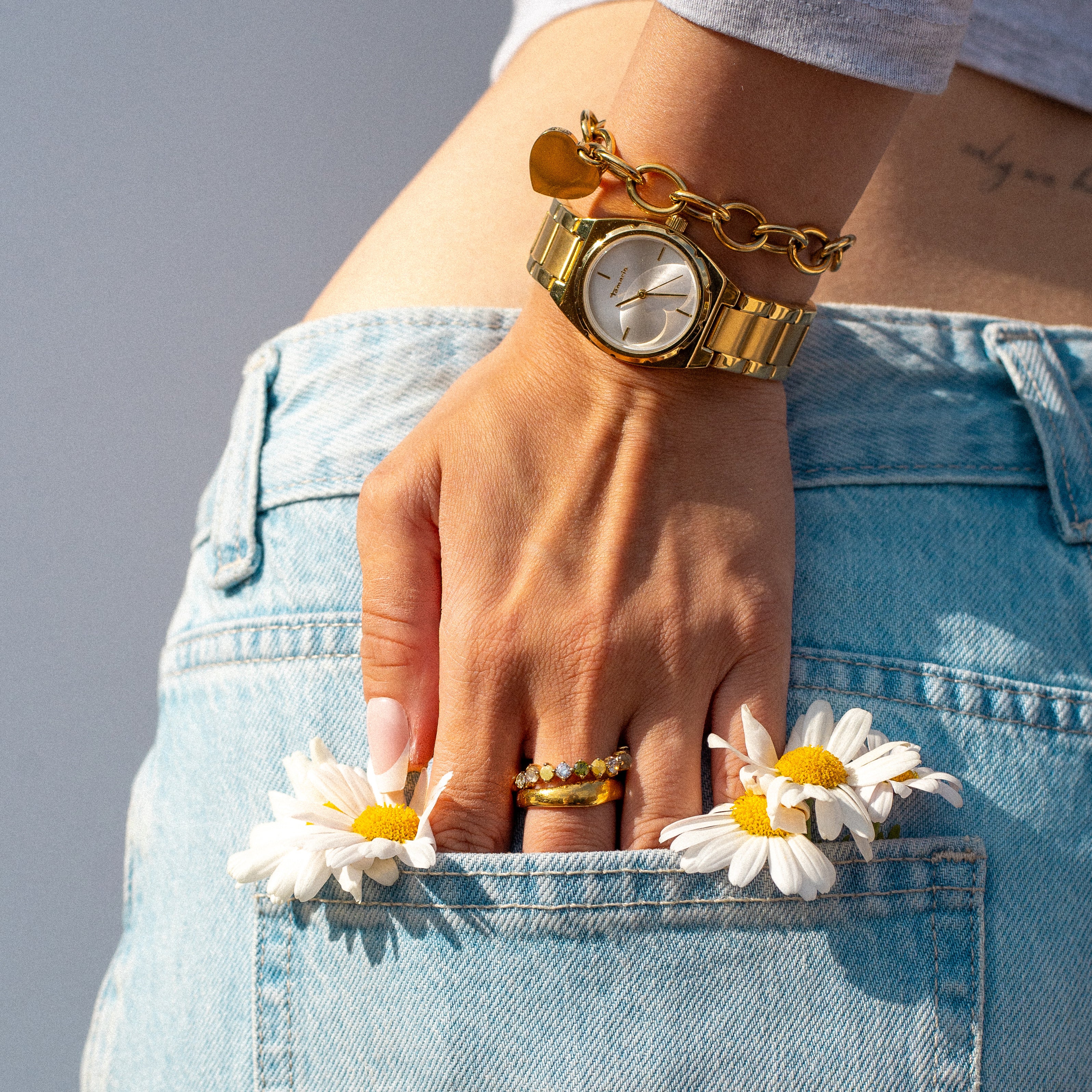 Shop-the-Look mit goldfarbener Tamaris Uhr, Chunky Heart Armband von LIEBSKIND BERLIN und Ringen kombiniert zu sommerlichem Denim-Style mit Gänseblümchen.