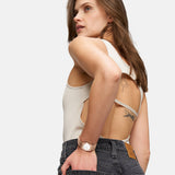 Frau in einem ärmellosen, rückenfreien Top und schwarzen Jeans, mit Tattoos und der Tamaris Armbanduhr - The Cool One von Tamaris, schaut zur Seite.