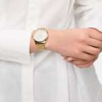 Nahaufnahme einer Person in einem weißen Hemd, die die goldene Tamaris Armbanduhr - Basic Elegance mit einem eleganten Perlmutt-Zifferblatt am linken Handgelenk trägt.