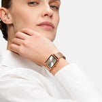 Frau im weißen Hemd zeigt die Tamaris Armbanduhr - Square Meets Mesh, eine rechteckige Damenuhr mit einem eleganten roségoldenen Edelstahlarmband aus Mesh von Tamaris.