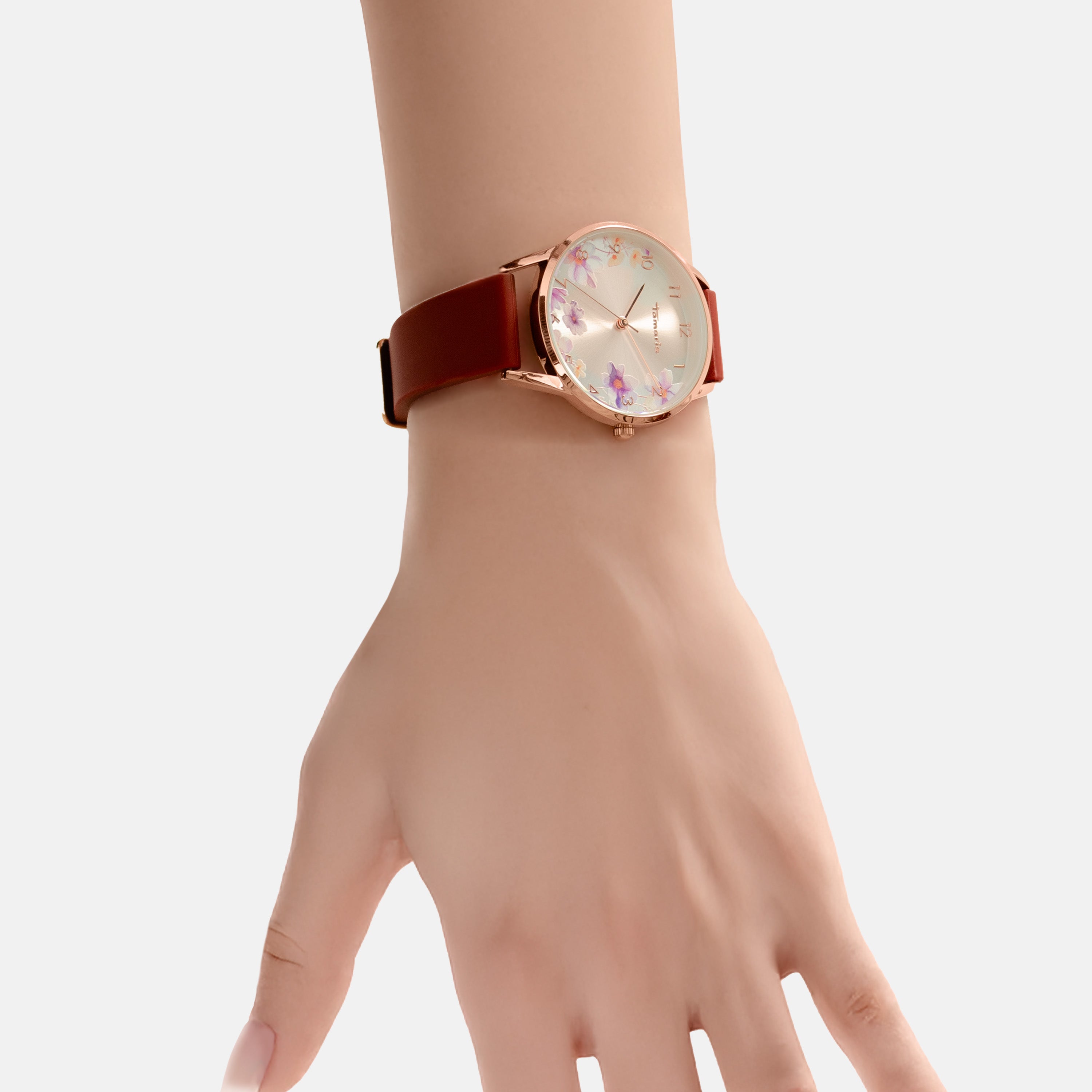 Eine Hand trägt die Tamaris Armbanduhr - The Flower von Tamaris mit einem braunen Silikonarmband und einem Blumenprint auf dem Zifferblatt.