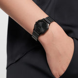 Person trägt eine Tamaris Sparkling Octavia Armbanduhr mit sechseckigem Zifferblatt und schwarzem Armband, Hand in der Tasche.